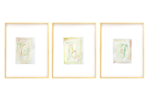 Set of three framed abstract watercolor paintings with pastel turquoise, pink, green, and yellow hues in white mats and gold frames.