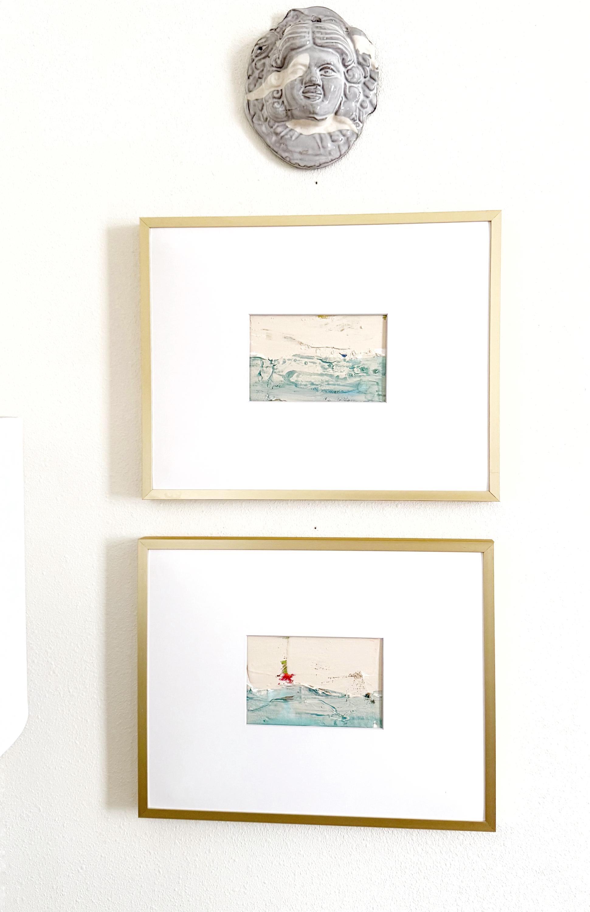 Original abstract mixed media landscape paintings set of 2 in gold frames with white mats, featuring muted blue and green hues and gold ink accents.