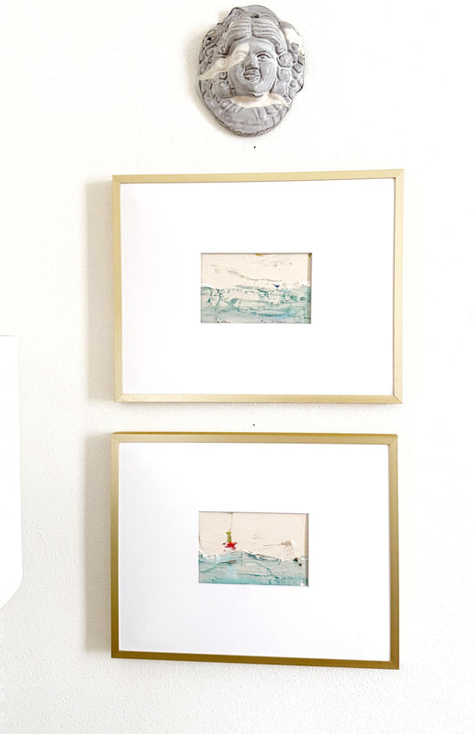 Original abstract mixed media landscape paintings set of 2 in gold frames with white mats, featuring muted blue and green hues and gold ink accents.